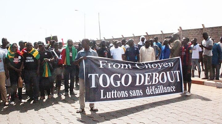 Eine Gruppe Menschen bei einer Demo, vor ihnen ein Transpi mit der Aufschrift Front Citoyen Togo Debout