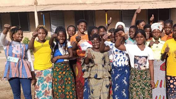 Eien Gruppe von Frauen aus Burkina Faso steht vor einem Haus