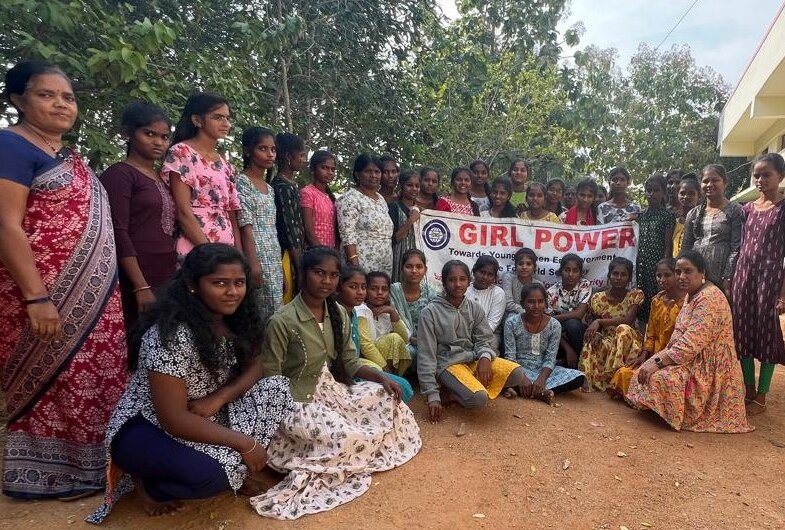 Eine Gruppe von indischen Mädchen und Frauen stehen in einer Reihe und haben ein Plakat in der Hand auf dem steht "Girl Power"