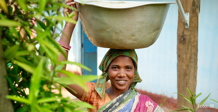 Eine indische Frau trägt eine Schüssel Waser auf dem Kopf