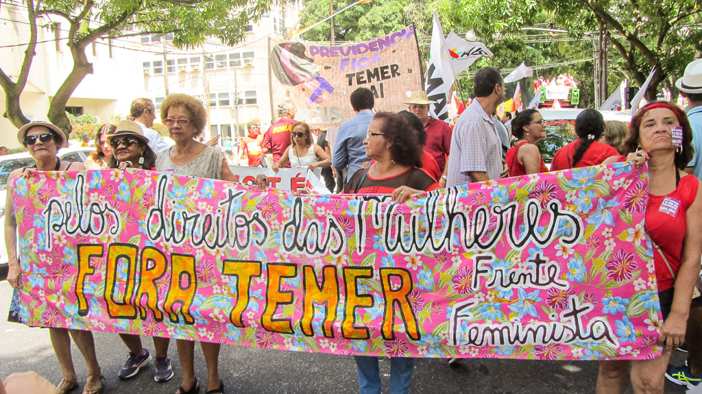 Eine Gruppe Frauen auf einer Demonstration für Frauenrechte mit buntem Transpi