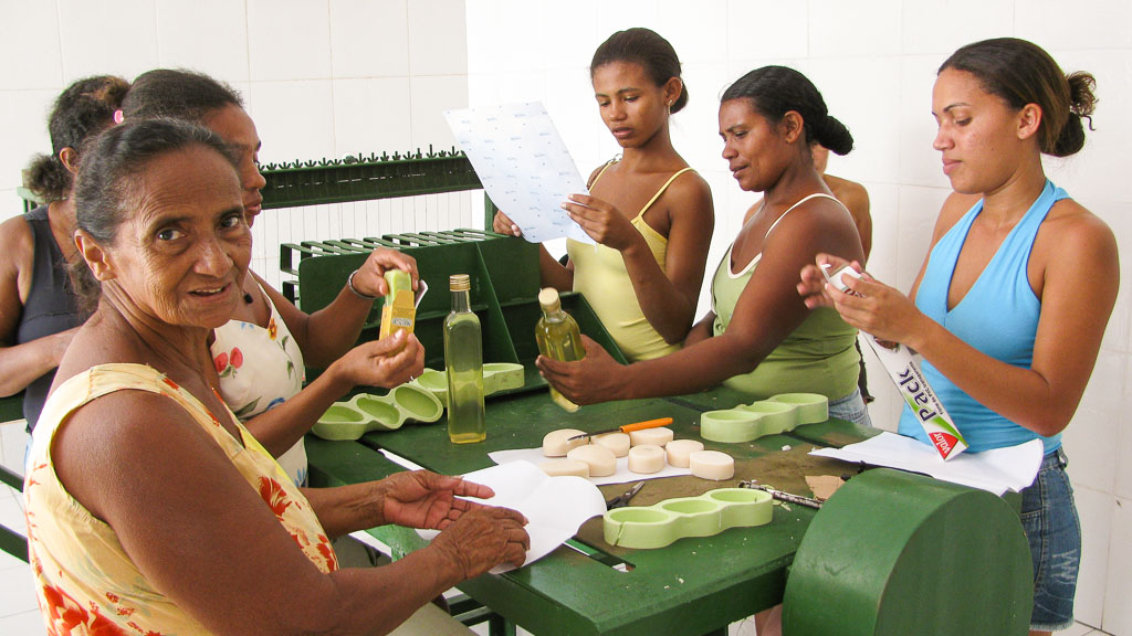 6 Frauen stehen um einen Tisch und produzieren Seife