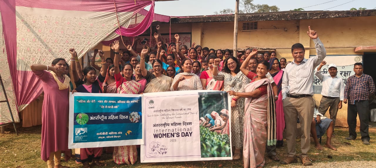 Eine Gruppe von Personen, mehrheitlich Frauen und indisch gekleidet jubelt und hält Transpis zum International Womens Day hoch