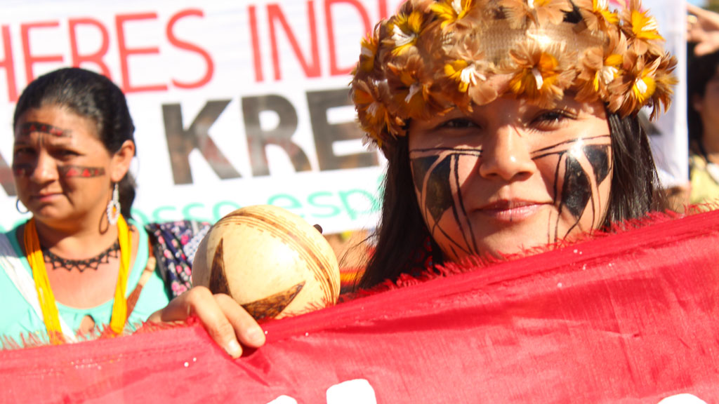 Zwei Indigene halten ein Transpi auf einer Demo